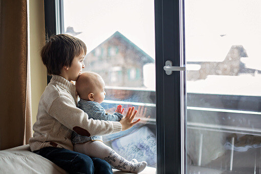 two young kids looking out window