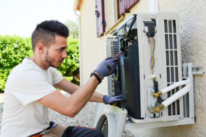 air conditioning technician repairs outdoor component of AC system