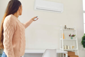 woman in sweater adjusts ductless heating system