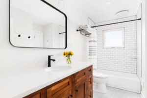 A cozy farmhouse bathroom with a wood cabinet, marble countertop, and subway tile shower.