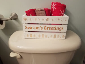 wood box with seasons greetings and red towels on toilet